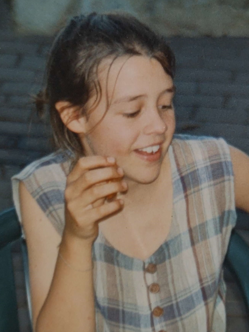 A childhood photo of Sophie Vivian as she smiles and looks to the side while having a meal.