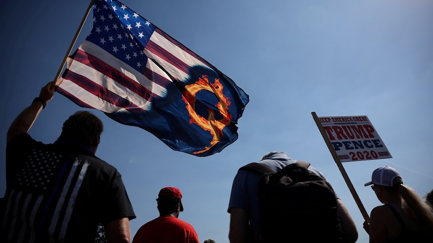 A supporter of President Donald Trump holds a US flag with a reference to QAnon during a Trump 2020 Labor Day cruise rally.