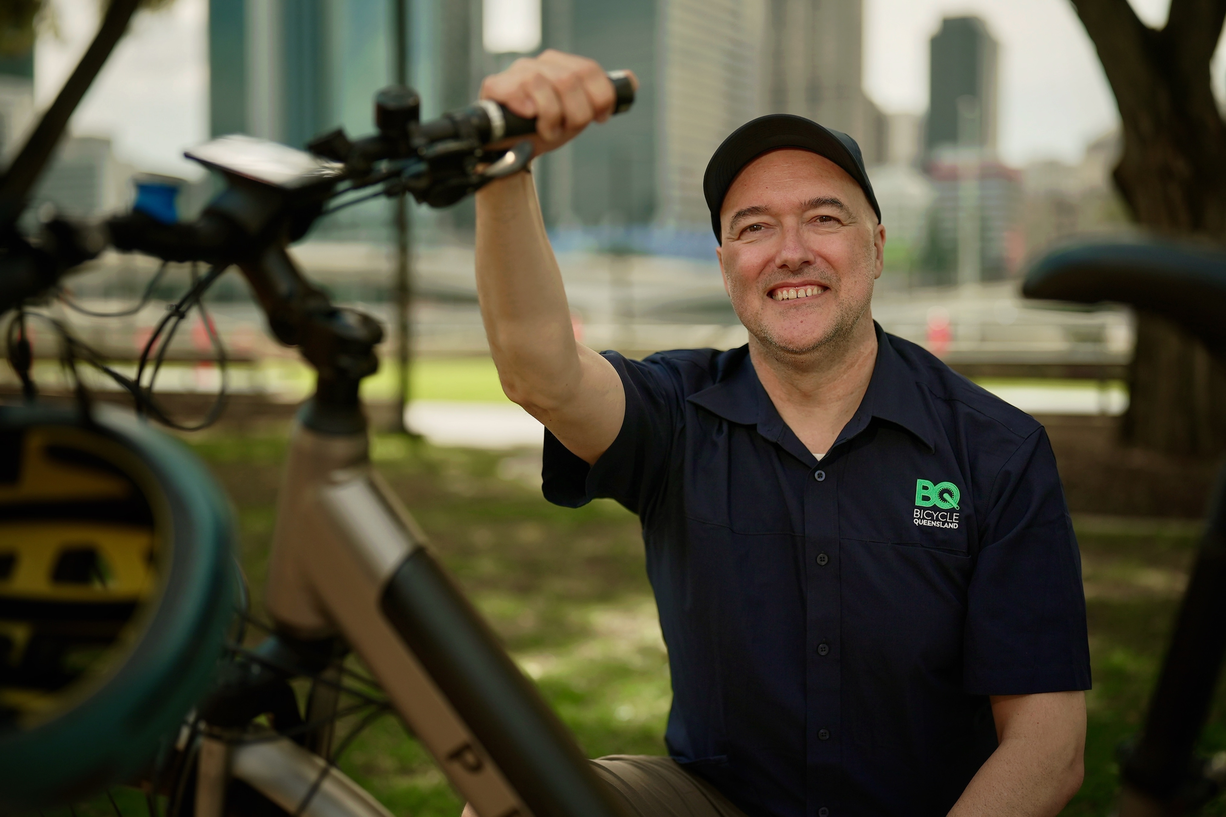 Matthew Burke smiling, holding a bicycle by the handles. 