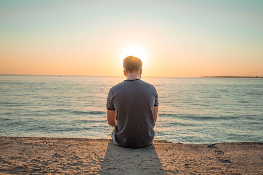 Man sitting, looking at the ocean