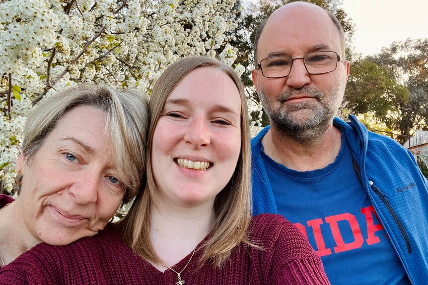 Jessica Horner smiles for a selfie with her mum and dad, who are either side of her, also smiling