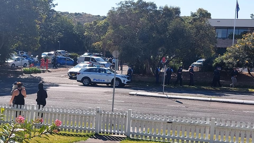 Police cars and police officers gather outside an office building.