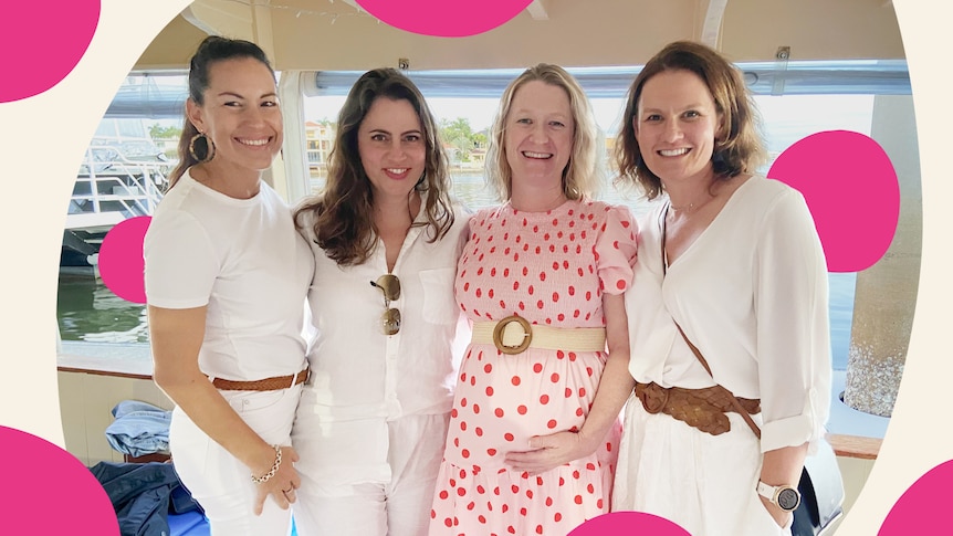 A pregnant woman in a pink dress surrounded by her friends.