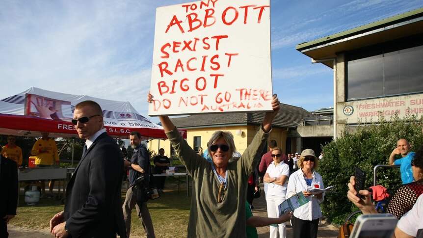 A protester with a sign stands outside voting booths in Tony Abbott's electorate of Warringah.