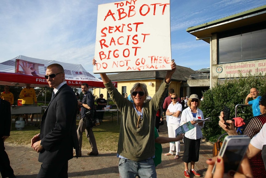 A protester with a sign stands outside voting booths in Tony Abbott's electorate of Warringah.