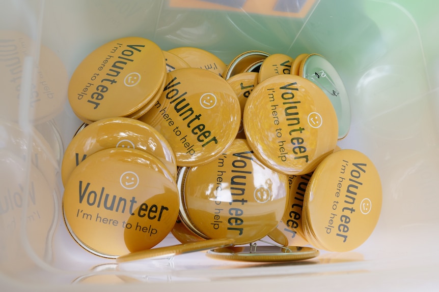 Photograph of a pile of badges with the word 'volunteer'.