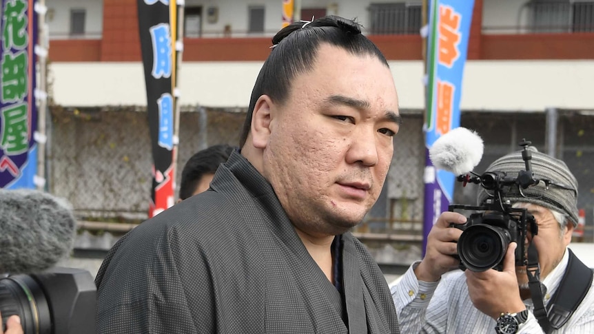 Sumo wrestler Harumafuji looks at the camera while surrounded by a number of other photographers.