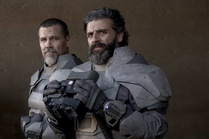 Actors Josh Brolin and Oscar Issac wearing grey futuristic suits of armour.