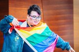 Luke Mayman holding a rainbow flag