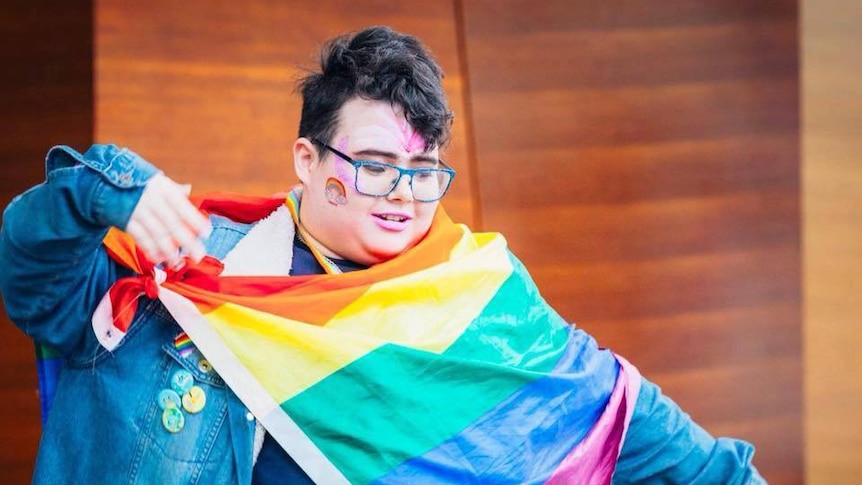 Luke Mayman holding a rainbow flag