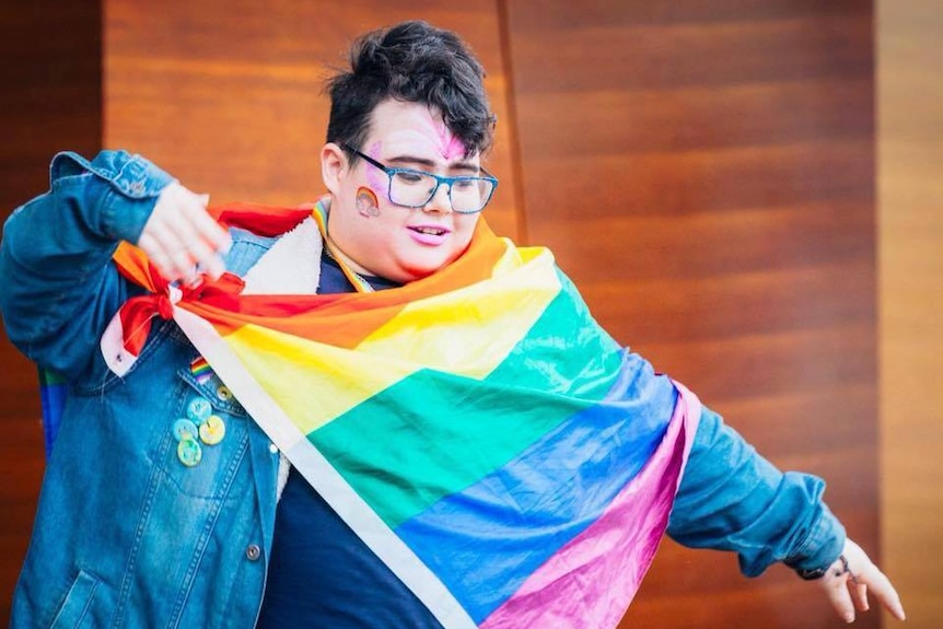 Luke Mayman holding a rainbow flag