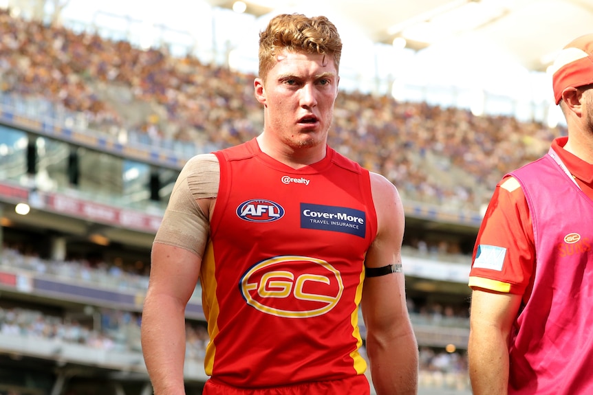 Gold Coast Suns player Matt Rowell leaves the AFL field with a trainer.