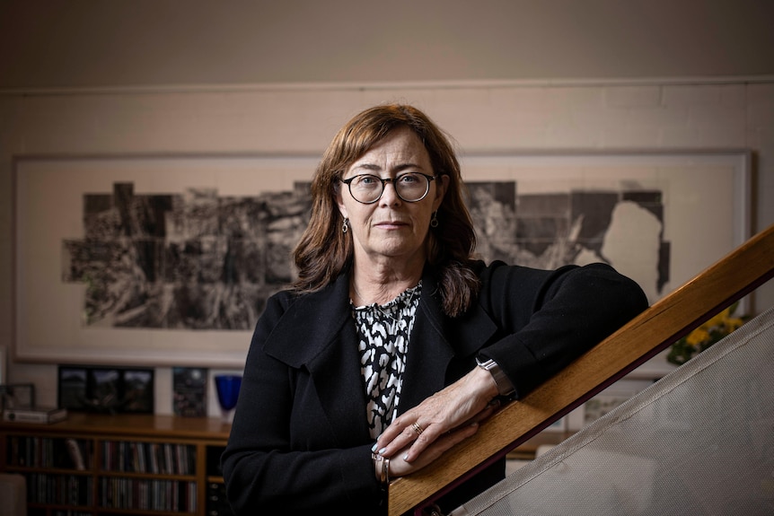 A woman wearing glasses and a black blazer.