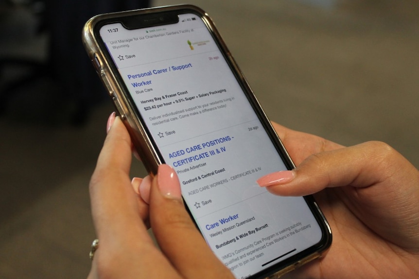 a hand holding a mobile phone with list of carer positions