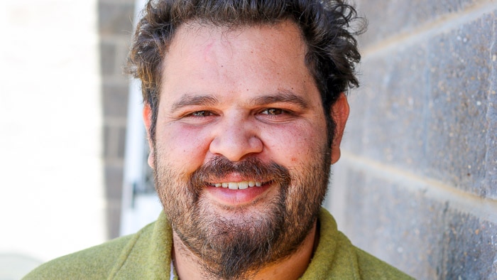 Closeup photo of Robert Clayton standing in front of brick wall.