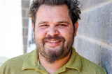 Closeup photo of Robert Clayton standing in front of brick wall.