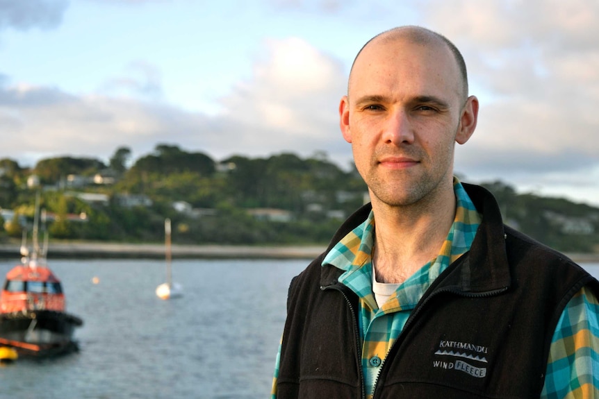 A man stands in front of a waterway.