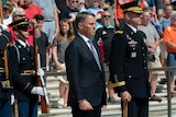 A white man in a suit stands in front of a crowd with several military officers in Arlington National Cemetary