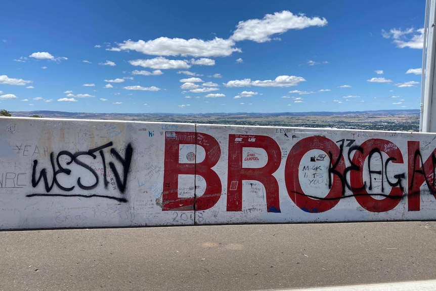 Large spray painted words 'West' and 'Keagan' partially cover the word 'Brocks' on a low concrete wall.