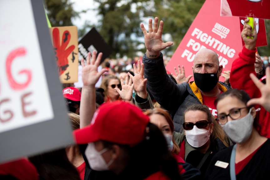 A crowd of people with placards, with many of them holding up the number five.