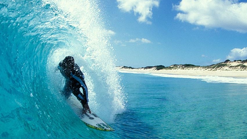 Surfer at catches a wave at Martha Lavinia Beach, King Island, Tasmania.