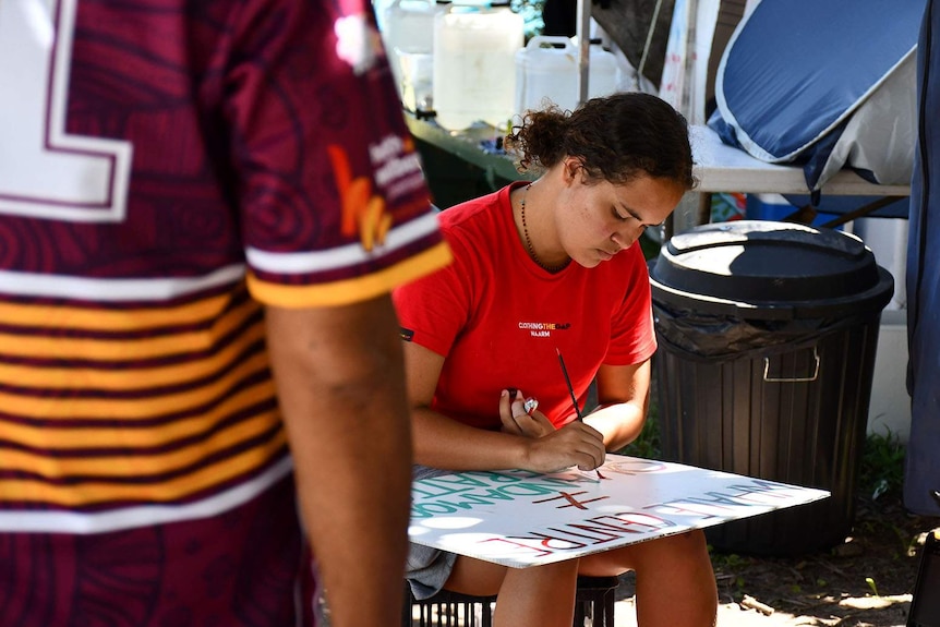 A young woman painting a sign