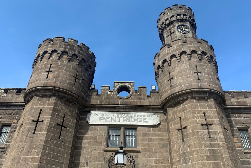 Looking up at the bluestone walls and guard towers of Pentridge, with a blue sky overhead.