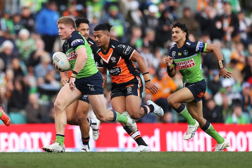 A man runs the ball during a rugby league match