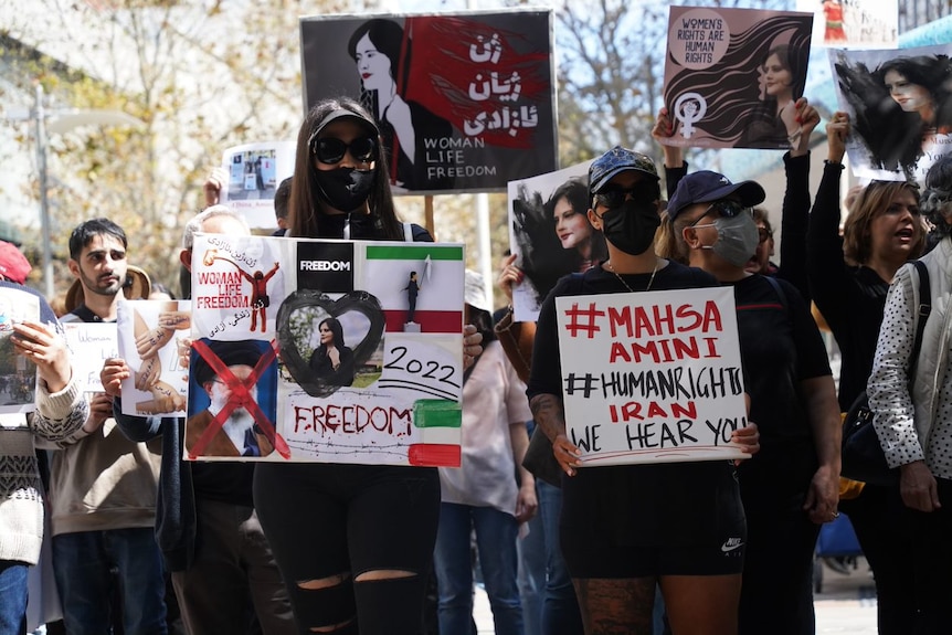 Protesters wearing black masks, holding up signs.