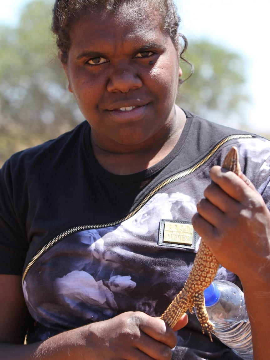 An Indigenous woman holding a sand goanna.