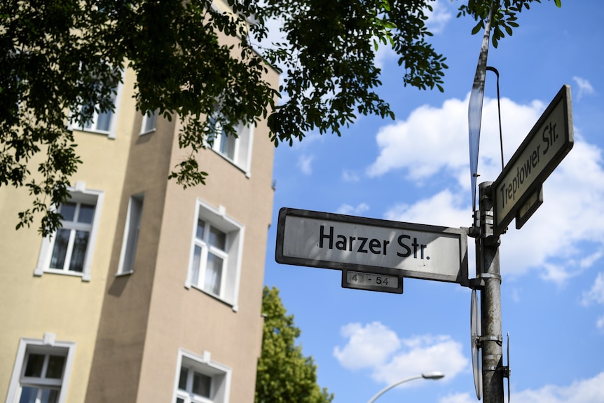 upward view of streets signs on the corner of Berlin street with an apartment block in the background. 