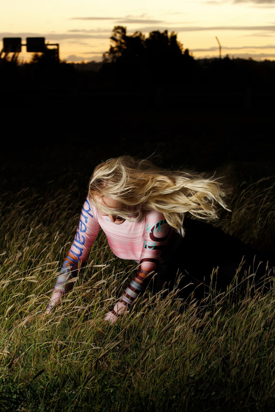 A woman in Higgins' pink gradient nylon top falls in a wheatfield at sunrise.