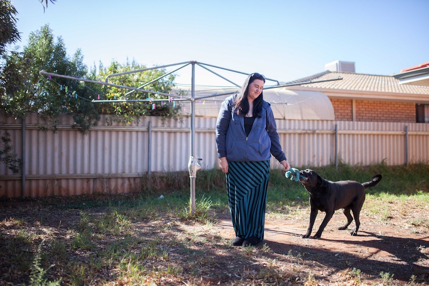 Cashless welfare card trial participant Sylvia Asusaar plays with her dog at her Kalgoorlie home.