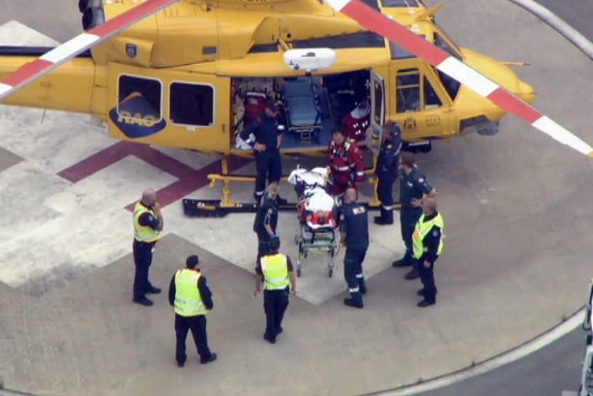 An injured person being wheeled out of the rescue helicopter.