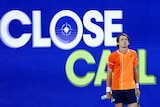 Alex de Minaur stands in front of a screen reading "Close call" at the Australian open.