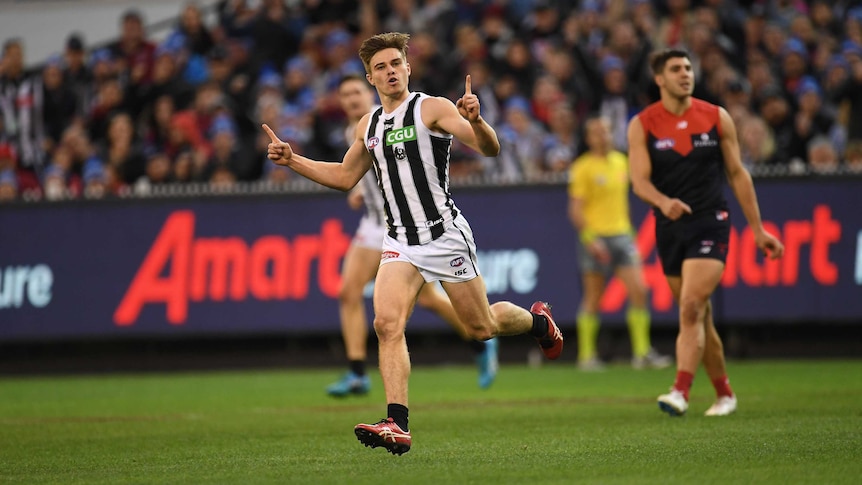 Josh Thomas celebrates a goal for the Magpies against the Demons.