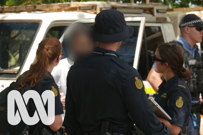 A man with a digitally blurred face talk to three people wearing Australian Border Force uniforms.