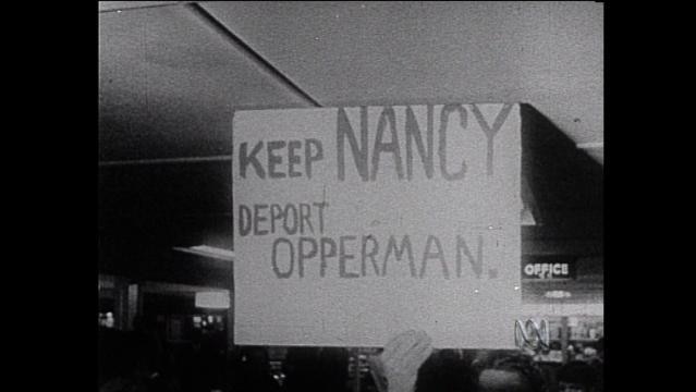 Old photo of hand holding protest sign that reads 'Keep Nancy, deport Opperman'
