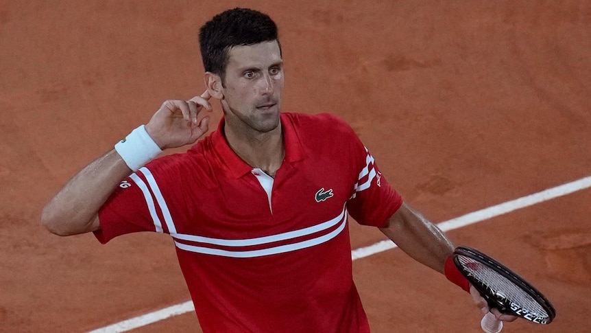 Novak Djokovic holds his hand to his ear