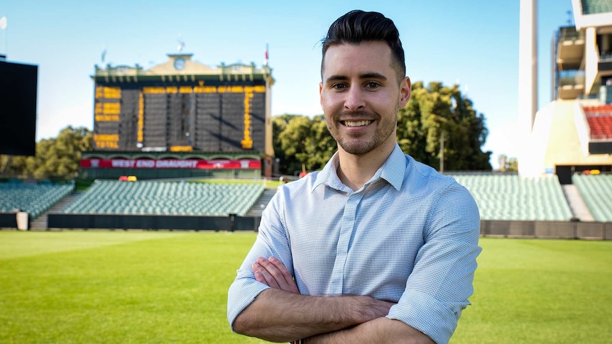 Aaron Bryans standing on the grass at the Adelaide Oval with the scoreboard in the background.