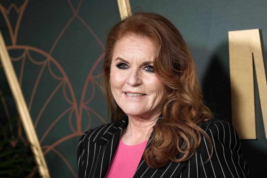 Duchess Sarah Ferguson standing in front of a dark background looking off-camera.