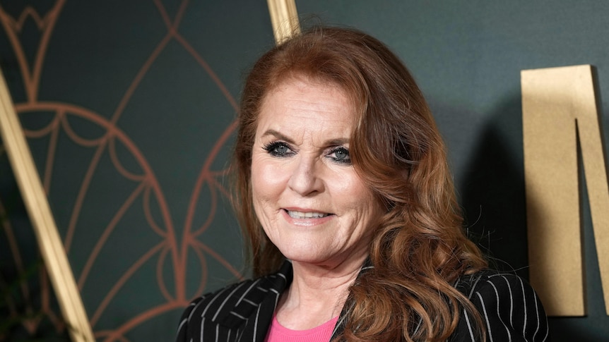 Duchess Sarah Ferguson standing in front of a dark background looking off-camera.