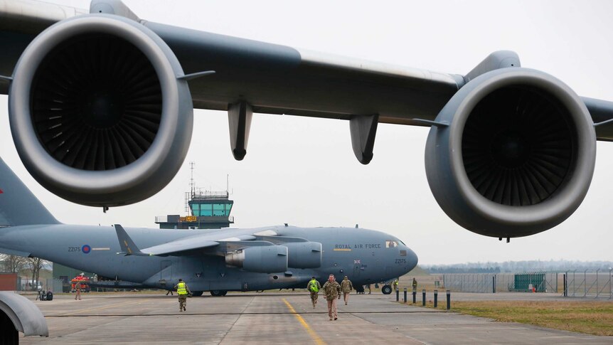 A broken down Royal Air Force C-17 stands in the foreground as another prepares to be loaded with French military equipment.