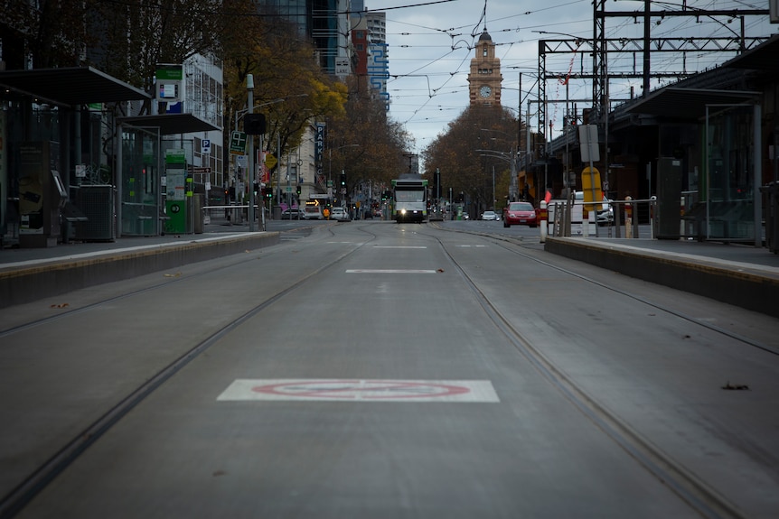 An empty street in Melbourne with a tram in the distance.