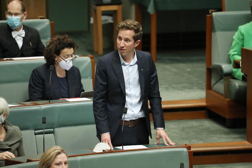 Max Chandler-Mather wearing a suit and no tie, standing and speaking in the house of representatives