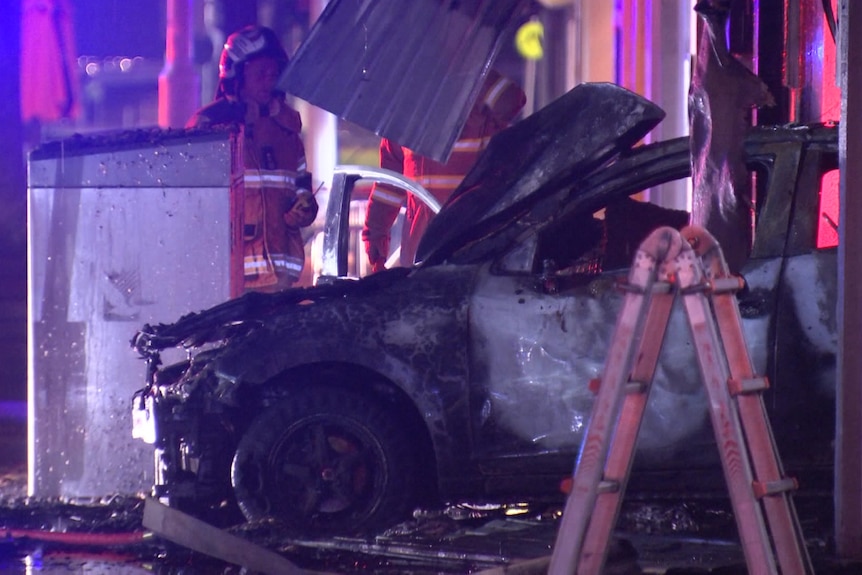 A burnt car in a shopfront.