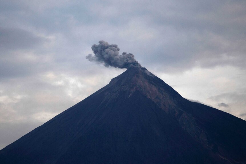 A volcano blows clouds of ash.