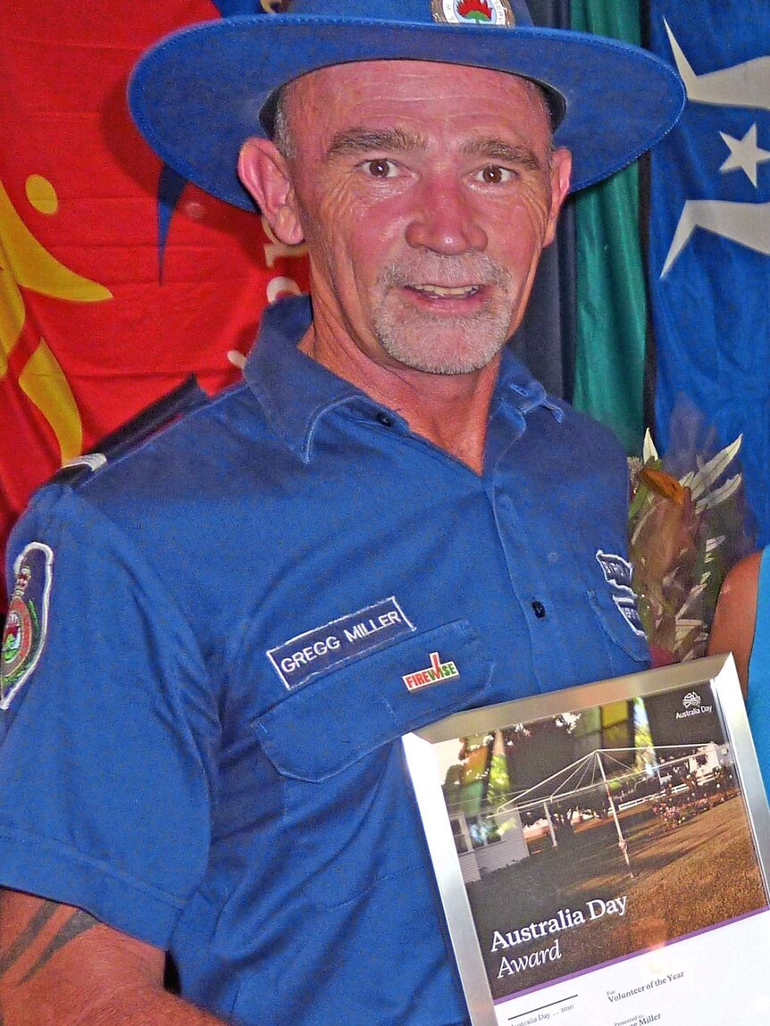 A man in a dark blue inform holding an award.