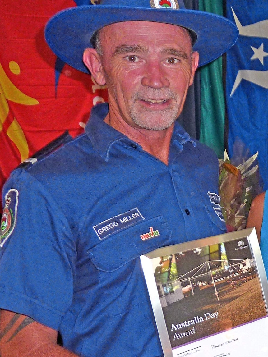 A man in a dark blue inform holding an award.