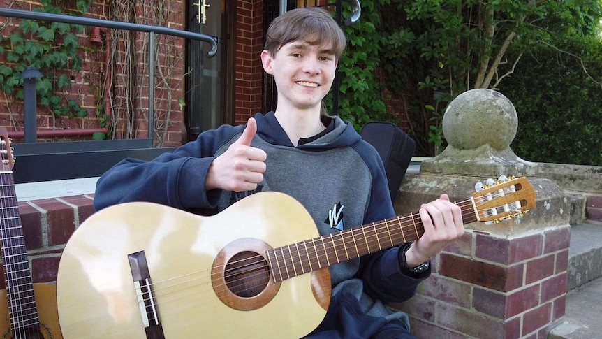 Tom Dunlop gives the thumbs up while holding a new guitar.